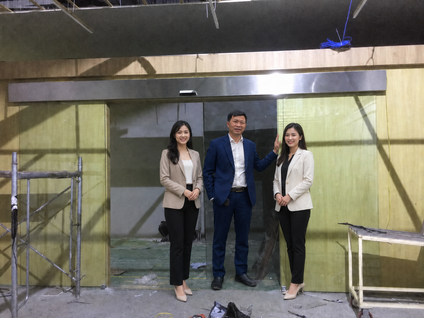 Ba nhân viên văn phòng đứng trước cửa kính tự động đang thi công trong công trình xây dựng